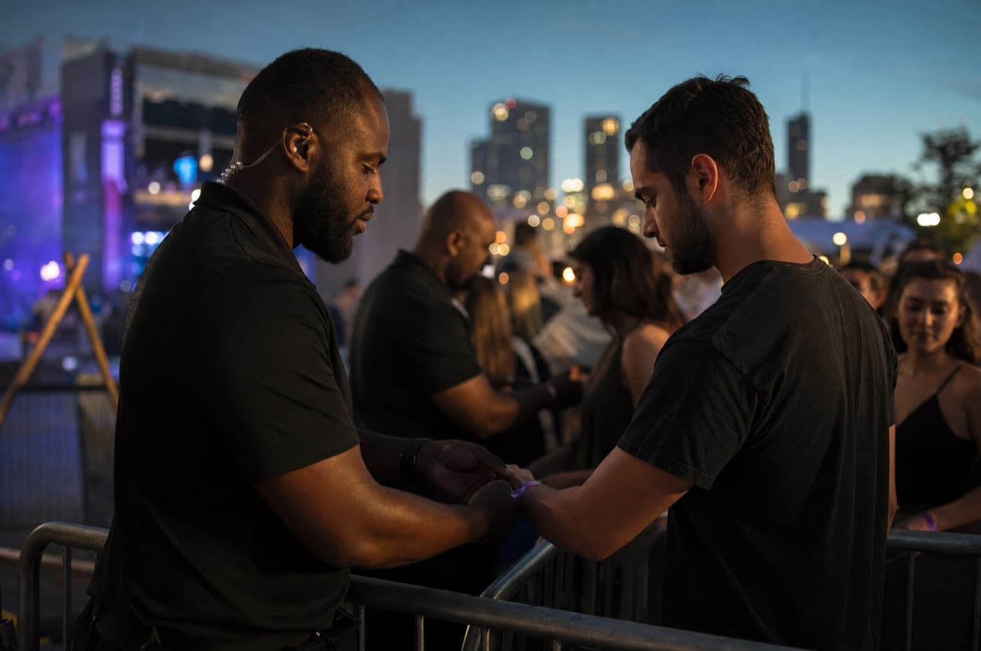 Event security staff checking credentials at a venue entrance at dusk.